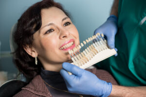 woman in dental clinic office. Dentist checking and selecting colour of the teeth. Dentistry